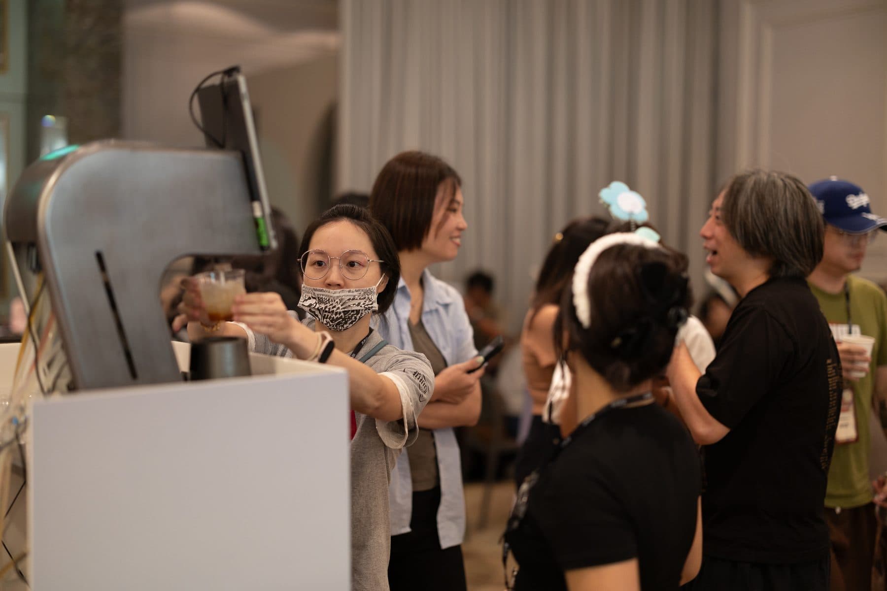 A guest lifting their finished drink from the smart bar while others wait nearby