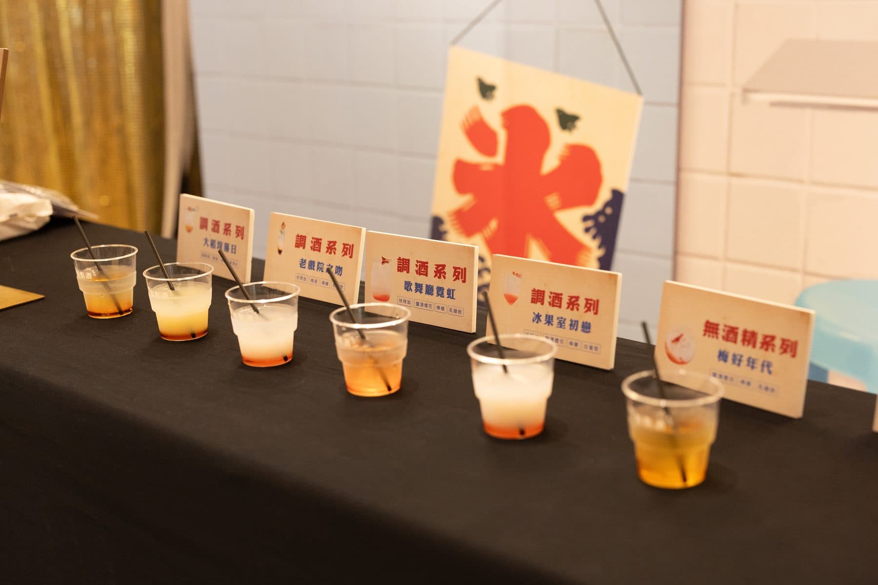 A row of finished drinks on a table, each with a name card marking alcoholic or alcohol-free