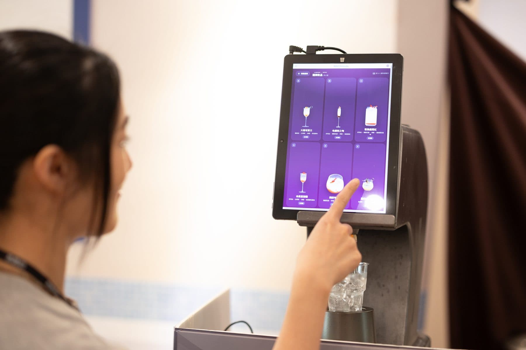 A guest choosing a drink on the smart bar touchscreen, three options shown