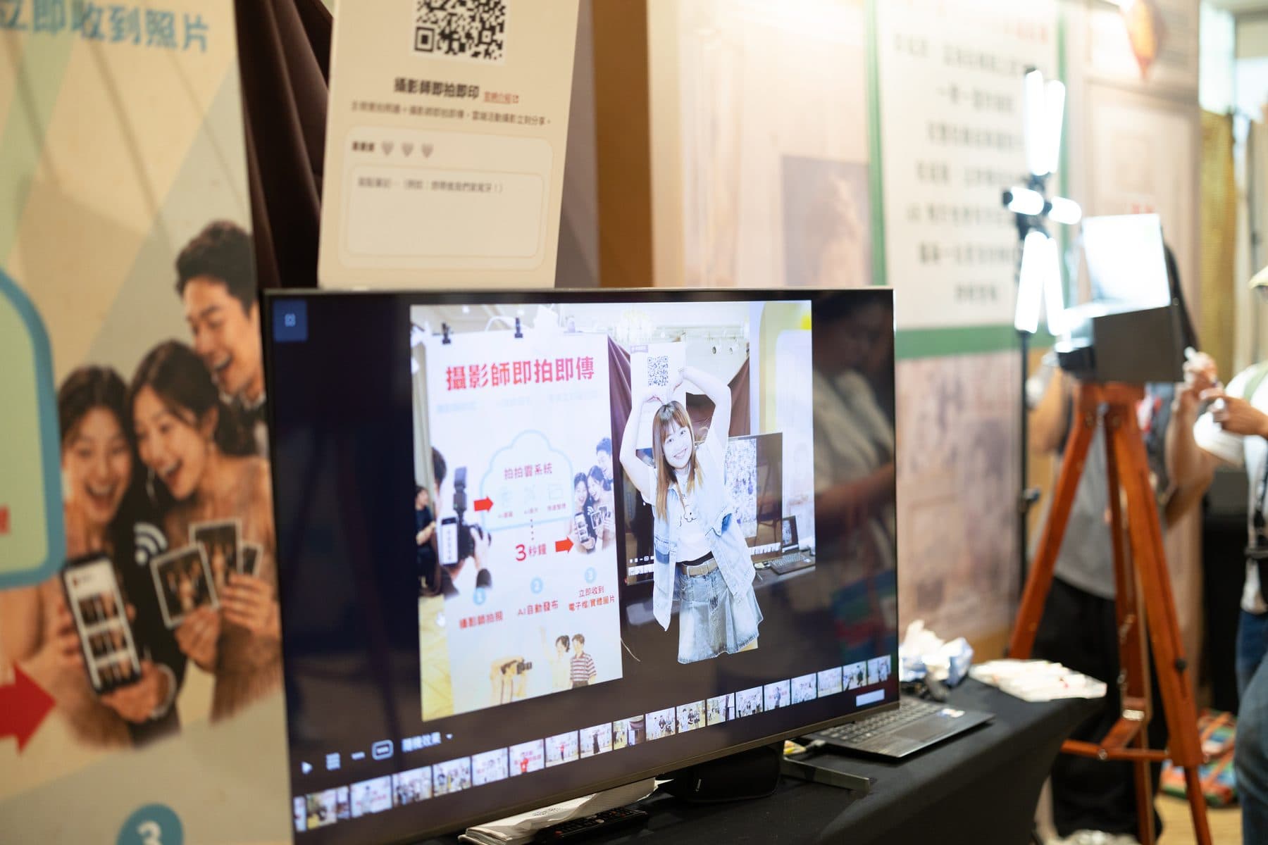 A large on-site screen cycling through photos just taken, beside a service board and camera stand