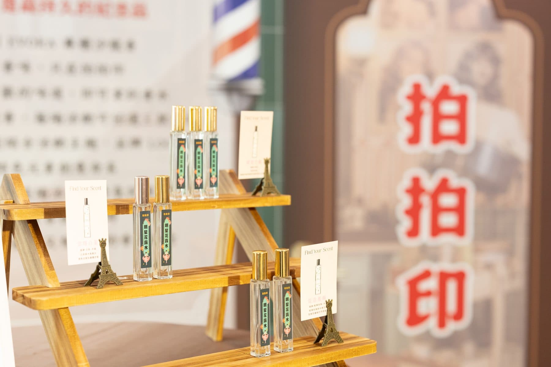 Fragrance bottles arranged on a tiered wooden stand with Find Your Scent cards and an Eiffel Tower ornament
