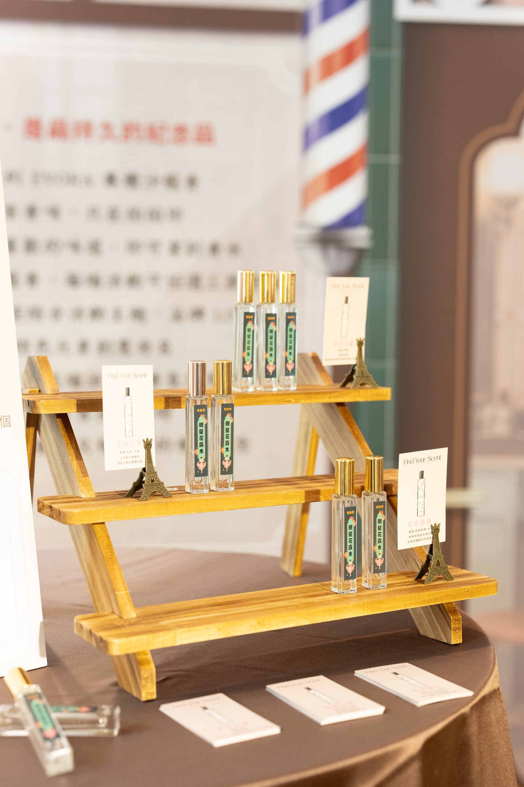 A tiered wooden stand holding custom fragrance bottles with explanation cards beside them