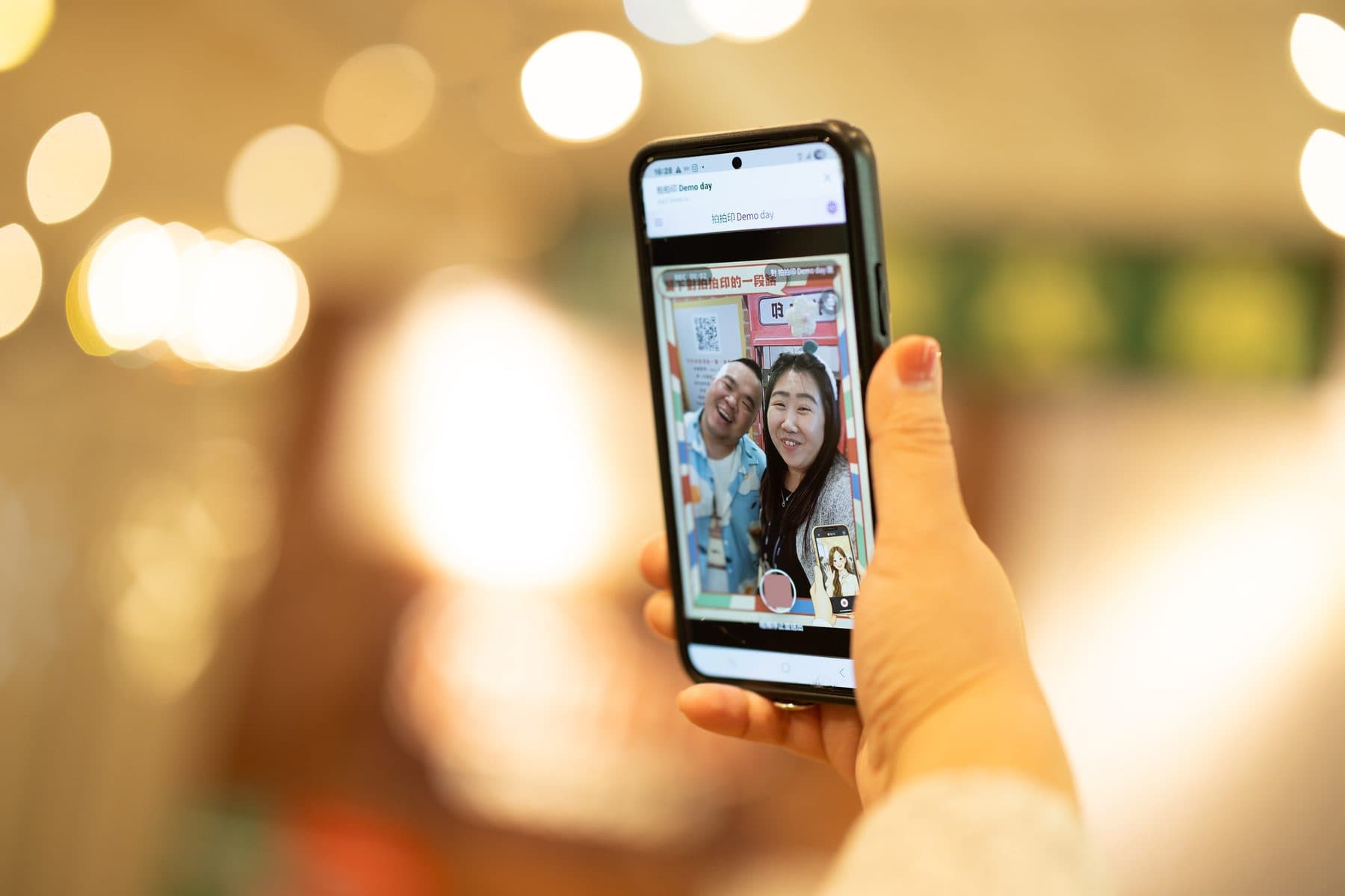 A phone screen showing two guests recording a video message, with the event QR code visible