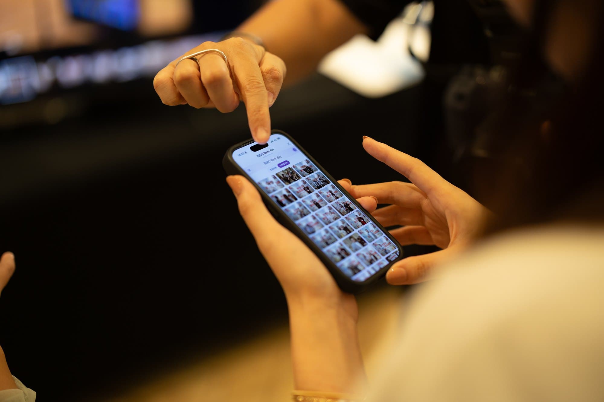 A guest scrolls a wall of event photos on their phone and taps the one they want printed