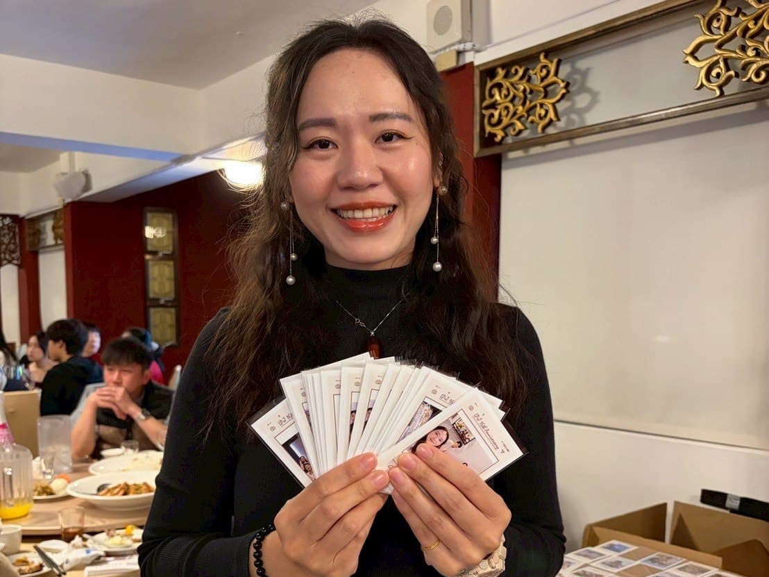 A guest fans out a thick stack of freshly printed photos in a banquet hall